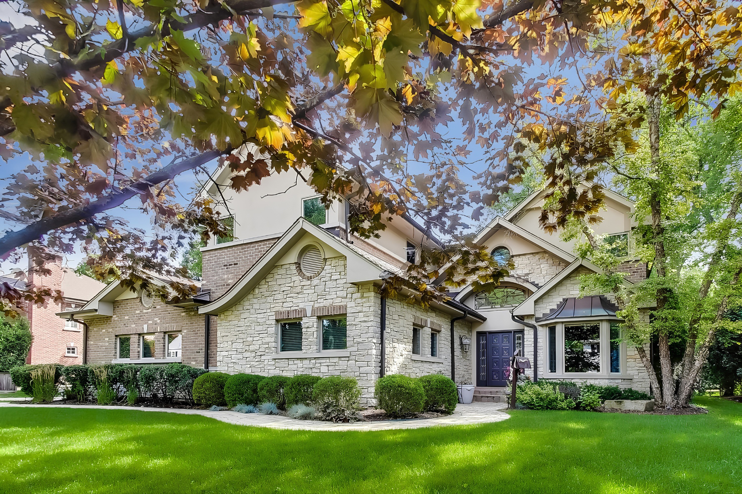Stone and brick home behind mature maples, a Gimbel Group listing